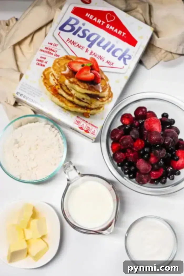 Effortless 5-Ingredient Bisquick Blackberry Cobbler 3 A box of Bisquick pancake mix is surrounded by bowls containing flour, mixed berries perfect for a blackberry cobbler, a cup of milk, a dish of butter, and a container of sugar. The ingredients are arranged on a white surface with a beige cloth in the background.