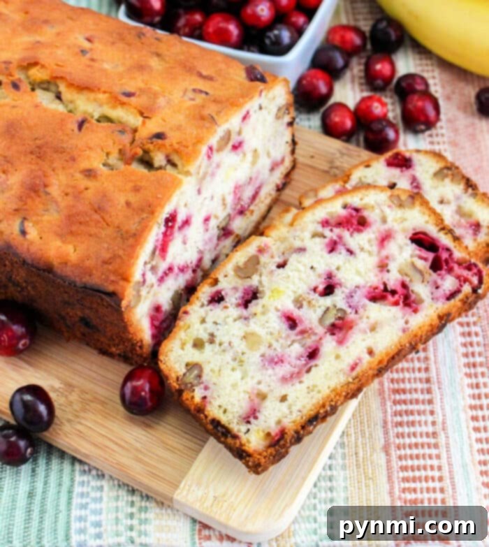 Cranberry Banana Bread recipe, featuring a close-up of a perfectly sliced loaf, highlighting its moist crumb and scattered cranberries.