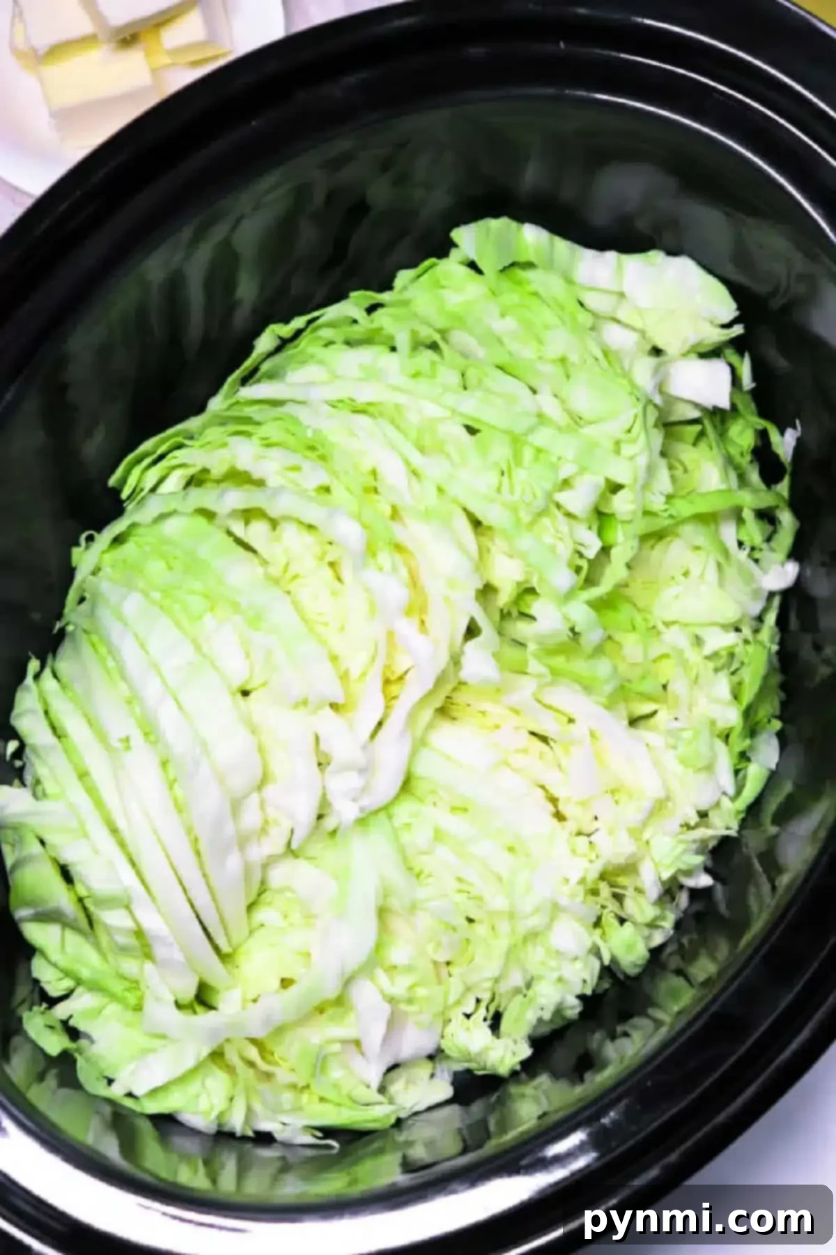 Savory Slow Cooker Cabbage 3 A heap of slow cooker cabbage rests inside a sleek black cooker, primed for a delicious transformation.