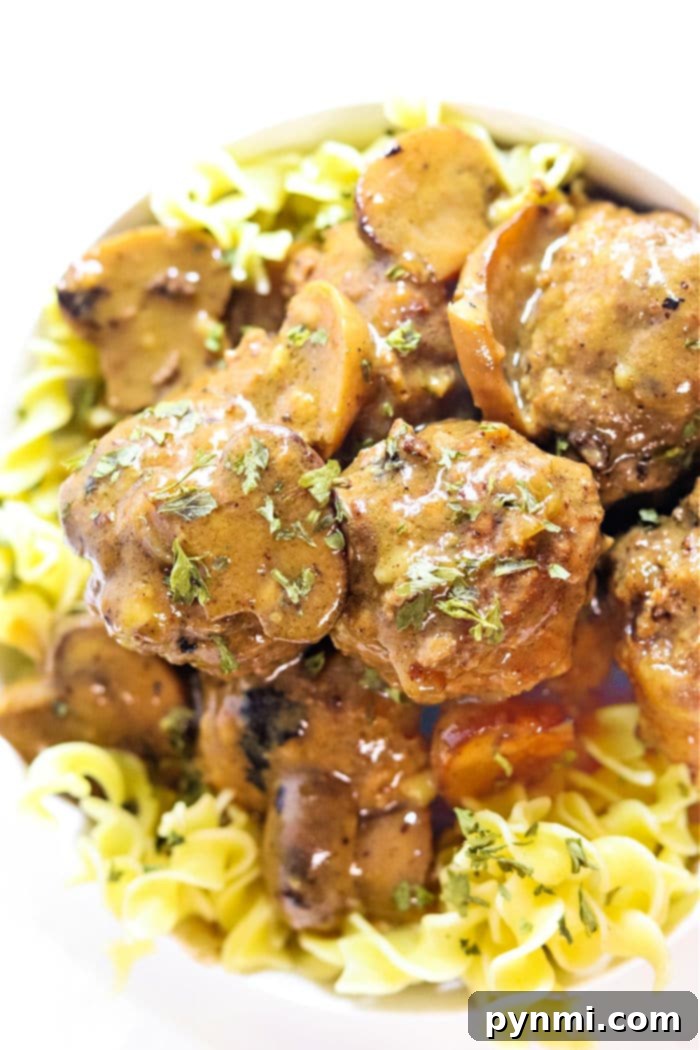 Slow cooker meatballs in gravy with a side of mashed potatoes.
