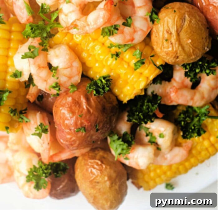 Air Fryer Seafood Boil Twist 9 Overhead shot of an air fryer shrimp boil on a rustic wooden surface, with a side of melted butter and lemon wedges, emphasizing its appealing presentation.