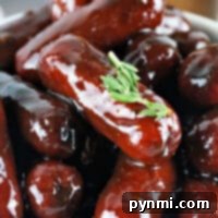 Glazed cocktail sausages piled on a plate, garnished with a sprig of thyme, make for delightful Traeger appetizers.