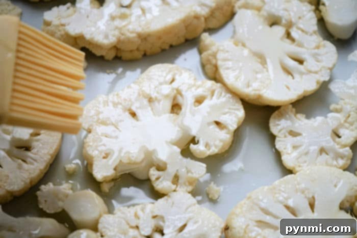 Seasoned cauliflower steaks arranged on a baking sheet, ready for cooking.