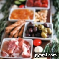 A charcuterie board shopping list featuring meats, cheeses, olives, nuts, and dips, all elegantly garnished with rosemary sprigs.
