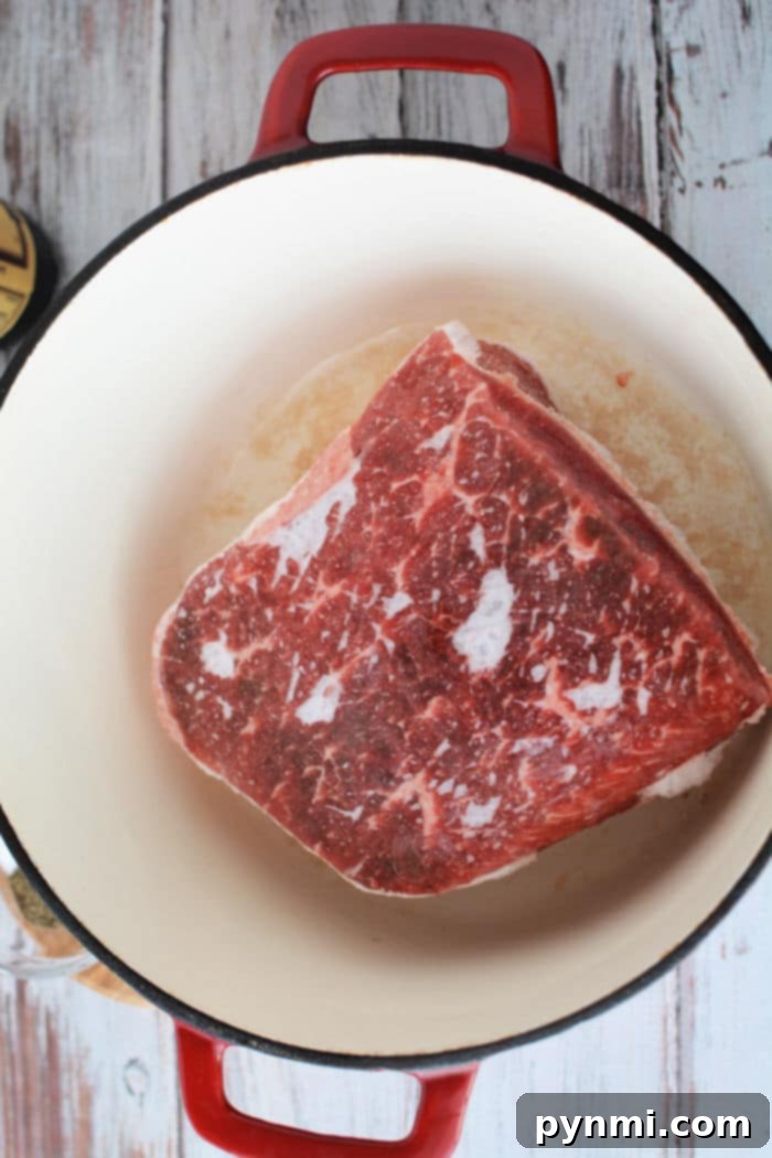 A Dutch oven containing a frozen roast with seasonings, ready for the oven.