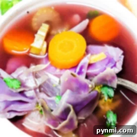 A vibrant bowl of Crockpot Cabbage Soup brimming with purple cabbage, carrots, celery, and herbs, showcasing its rich colors and hearty texture, ready to be served.
