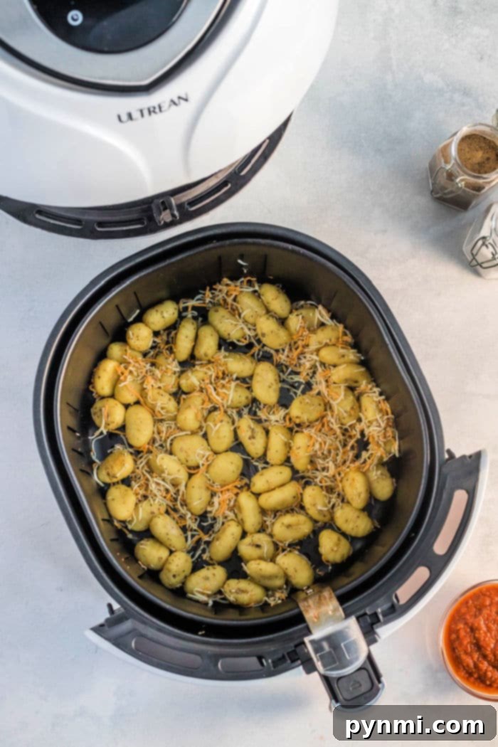 Shelf-stable gnocchi perfectly coated with olive oil and seasonings in an air fryer basket, ready for cooking.