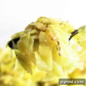 Close-up of cooked cabbage on a fork, seasoned with pepper, against a bright background, reminiscent of cozy crockpot cabbage recipes.