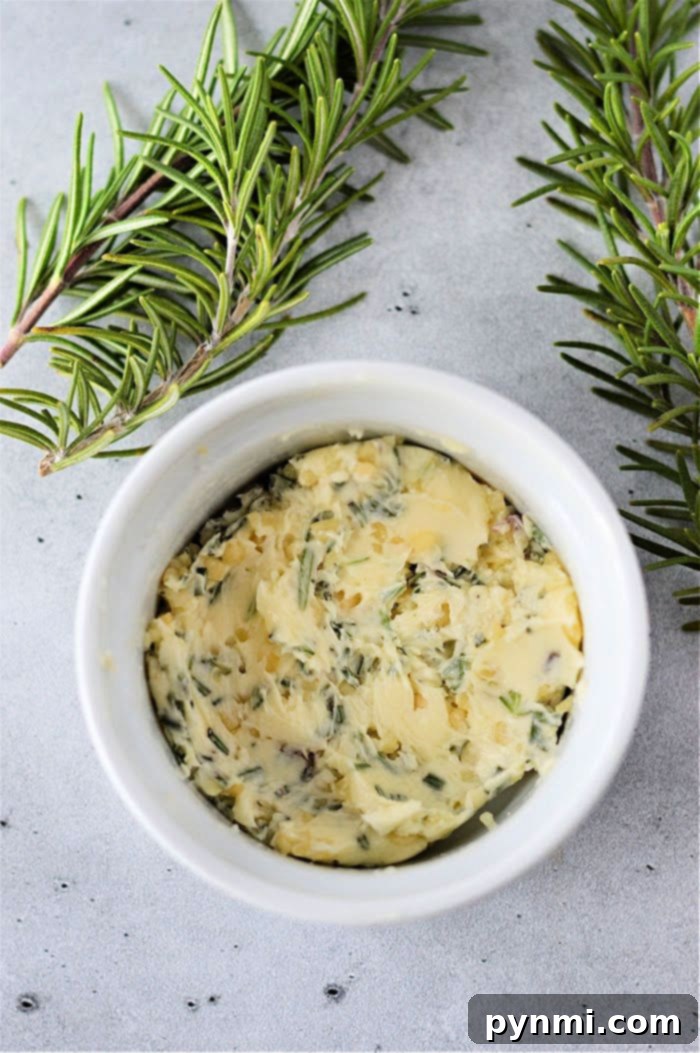 Herb-infused butter in a white ramekin, garnished with fresh rosemary sprigs on a light gray surface, is the perfect complement when you learn how to cook frozen steak to perfection.