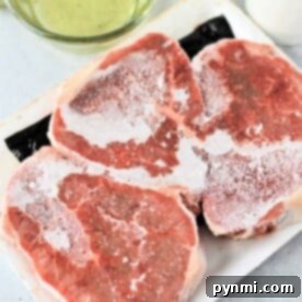 Three frozen steaks rest on a white tray, waiting to be transformed into a culinary delight. A bowl of olive oil sits nearby, ready for the first step in learning how to cook frozen steak to perfection.