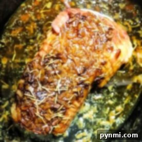 Pork roast topped with rosemary and onions, simmering in flavorful juices and Slow Cooker Pork Roast Onion Soup Mix for a savory, effortless meal.