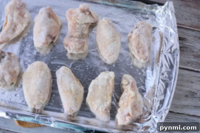 Frozen wings baking in the oven on a tray.