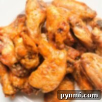 A plate of crispy, baked chicken wings coated in a glossy orange sauce.