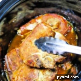 Ultimate Slow Cooker Ranch Pork Chops 8 Close-up of Slow Cooker Ranch Pork Chops in a cooker, being lifted with metal tongs.