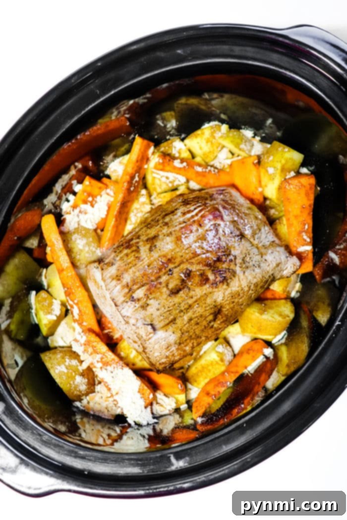 Close-up of a tender crockpot roast with gravy and a sprinkle of fresh herbs, ready to be served.