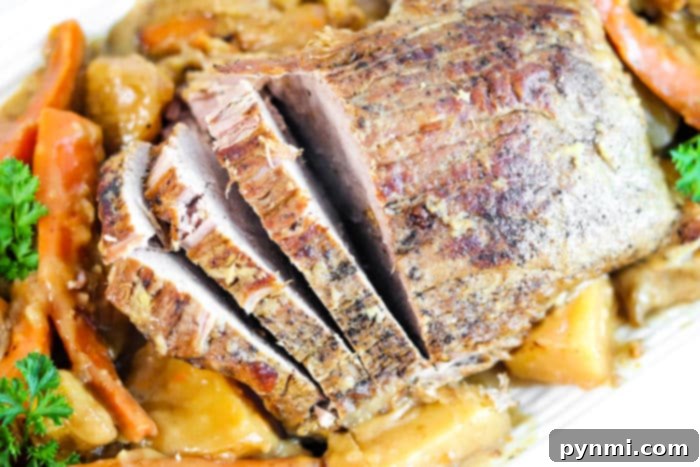 Large cut of beef cooking in a slow cooker with plenty of carrots and potatoes.