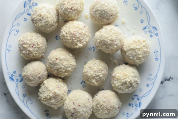 A serving of perfectly baked mashed potato balls, golden brown and garnished with herbs on a rustic plate.