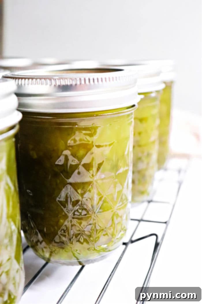 Sweet Heat Pepper Jelly 2 Canning jars filled with vibrant green pepper jelly, cooling on a rack