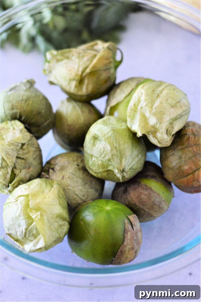 A close-up shot of roasted tomatillos on a baking sheet, showcasing their charred skins and soft texture, ready to be blended into a smoky salsa.