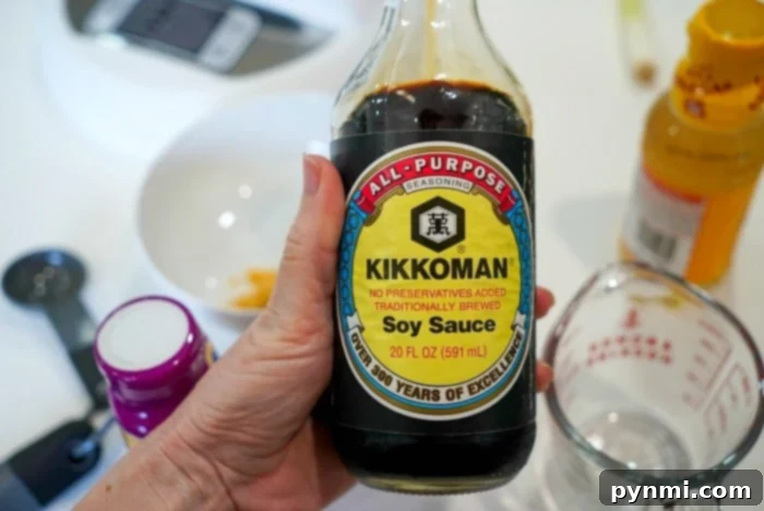 A bottle of soy sauce, essential for homemade teriyaki sauce, on a white surface.