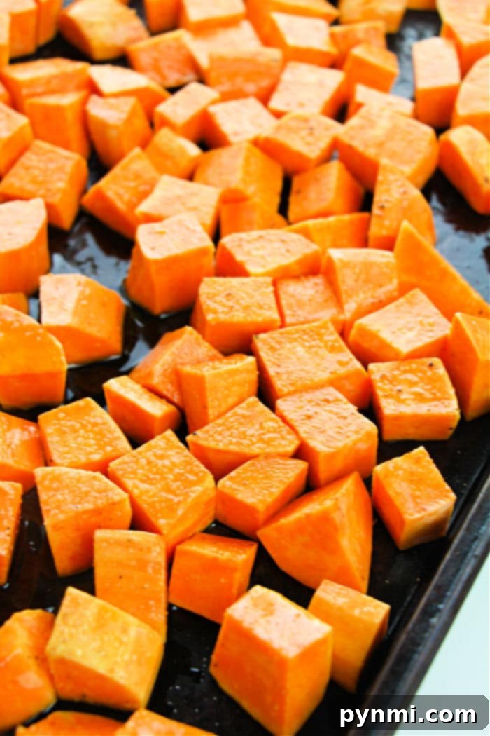 A wooden bowl filled with freshly roasted sweet potato cubes, some with a hint of herbs, ready to be served.