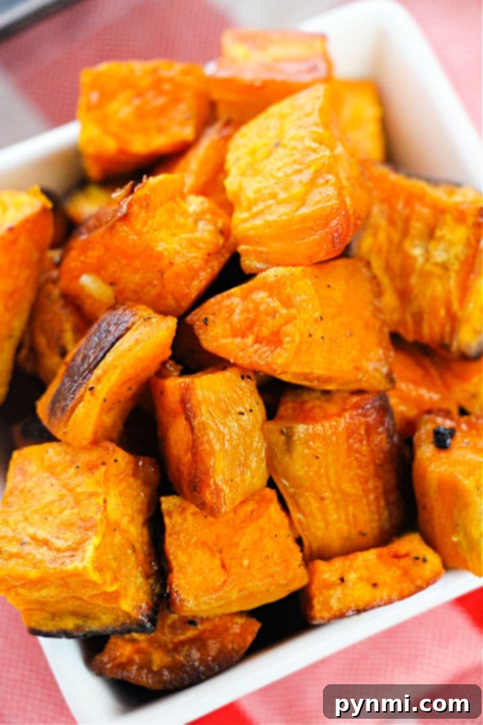 A close-up shot of roasted sweet potato cubes in a serving bowl, some pieces showing golden-brown edges, ready to be enjoyed.