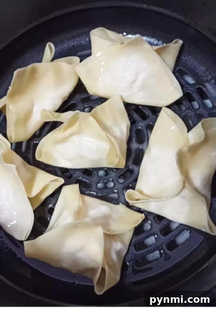 A close-up of a perfectly filled and folded Ninja Foodi crab rangoon before air frying.