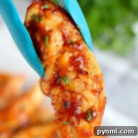 Naked Air Fryer Chicken 9 Close-up of grilled BBQ chicken held by blue tongs, garnished with herbs. This air fryer chicken recipe requires no breading, highlighting the perfect blend of smokiness and freshness.