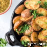 A bowl of seasoned air fryer fried potatoes garnished with fresh parsley, accompanied by a nearby bowl of spice mix.
