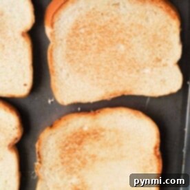 Four slices of golden-brown toast, perfectly crisped by making toast in the oven, rest on a baking tray.