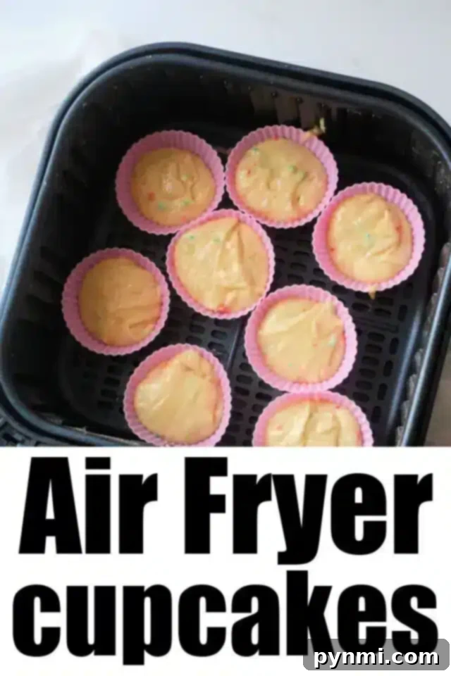 Effortless Air Fryer Cupcakes 5 An air fryer basket holds eight colorful silicone cupcake molds filled with cupcake batter. The text "Delicious Air Fryer Cupcakes" is prominently displayed at the bottom of the image.