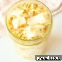 A glass jar filled with marinated cabbage cubes in herbs and spices sits enticingly on a light surface, reminiscent of quick pickled cabbage in its tangy allure.