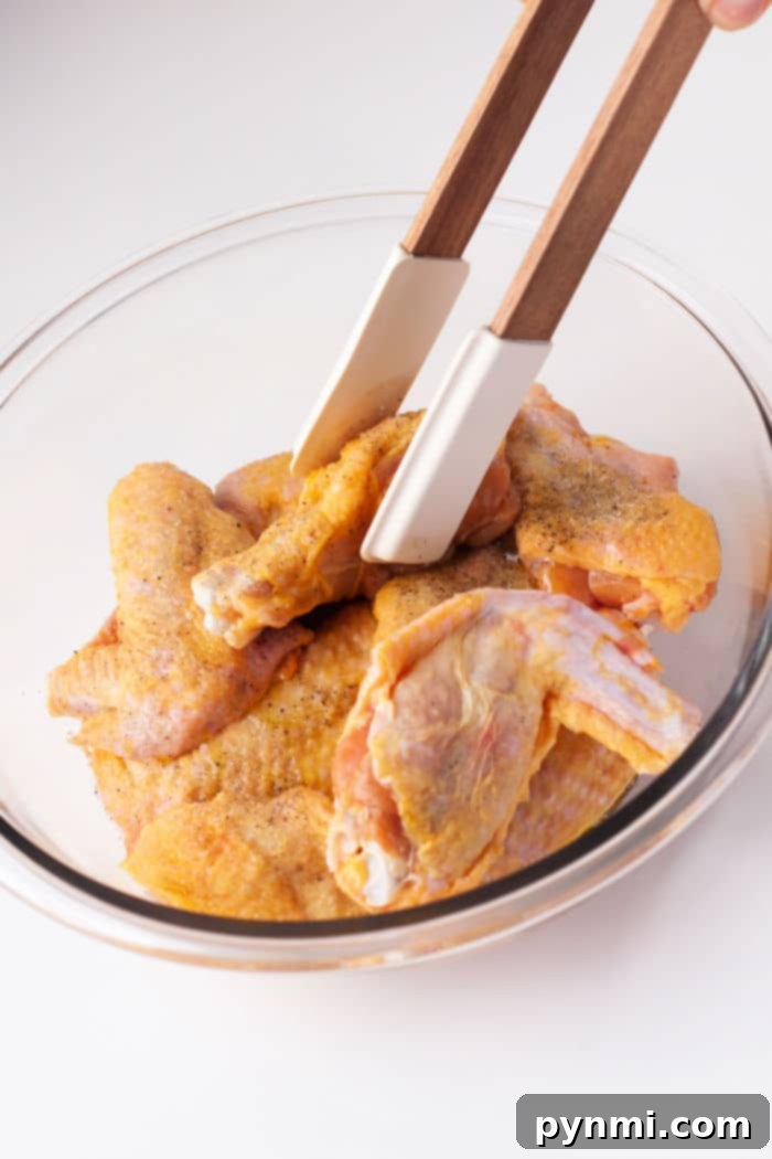 Cooking chicken wings in an air fryer basket, showing the dry-rubbed wings before sauce is added.