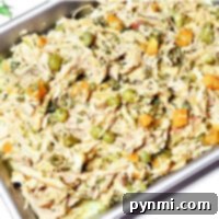 Wholesome Slow Cooker Chicken Meals for Your Dog 8 A crockpot dog food delight: a tray of shredded chicken with peas, carrots, and herbs, cooked to perfection.