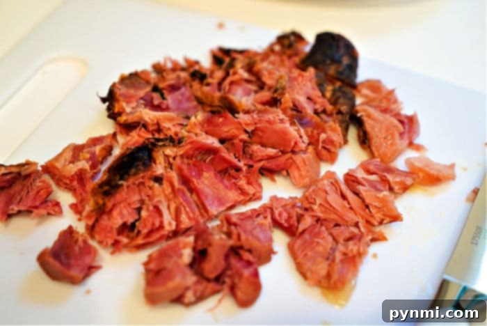 Unlocking the Flavor of Ham Hocks 5 Diced, smoked ham hock meat on a white cutting board, ready to be returned to the slow cooker soup or served.
