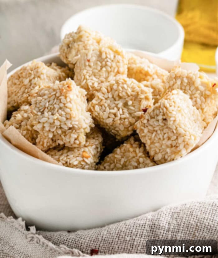 Golden Tofu Poppers 2 Crispy Baked Tofu Nuggets without Breadcrumbs, garnished with sesame seeds.