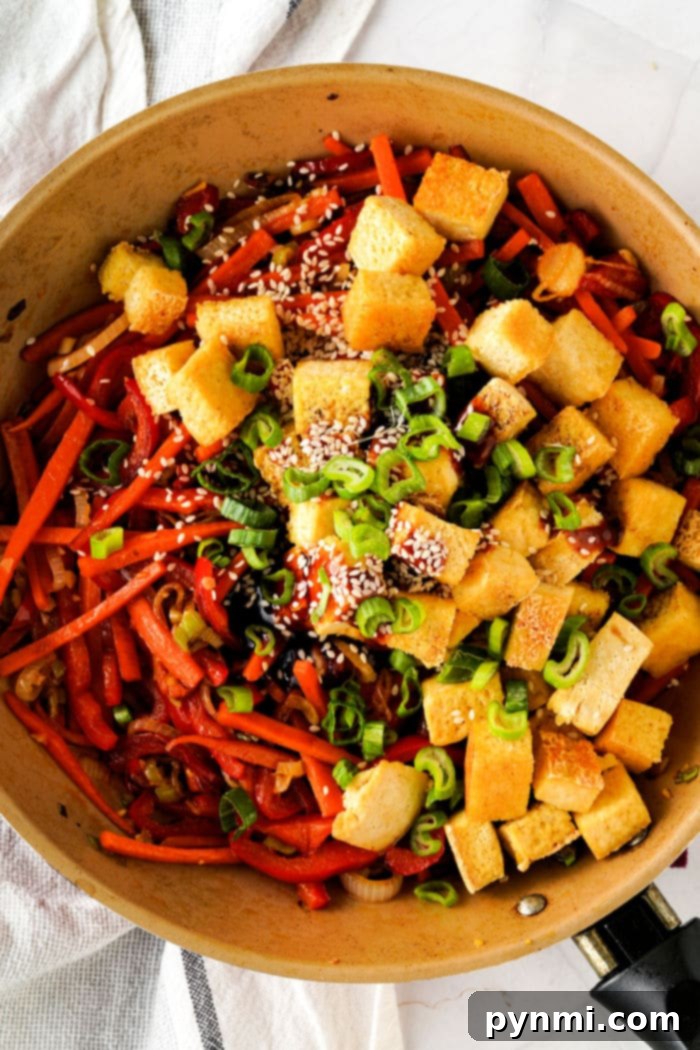 Sticky Teriyaki Tofu Lettuce Cups 5 A skillet with tofu cubes, green onions, sesame seeds, mixed vegetables, and a touch of tofu for that lettuce wrap vibe.