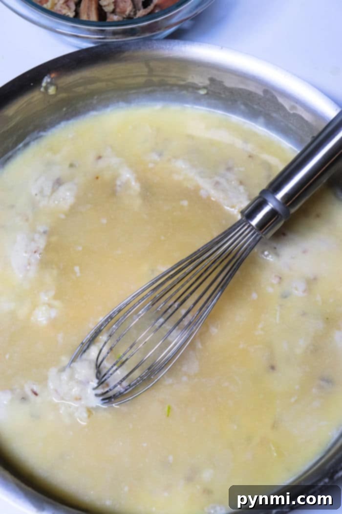 A bowl of freshly made chicken gravy, garnished with fresh herbs, ready for a comforting meal.