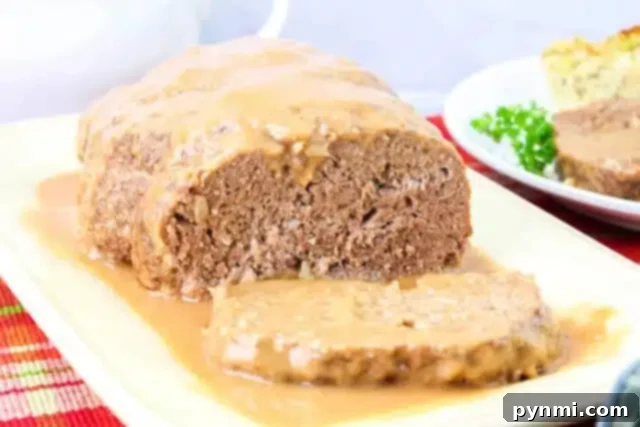 Foolproof Brown Gravy for Meatloaf 7 A plate of meatloaf topped with rich brown gravy, with one slice cut from the loaf. A partial view of a second plate featuring another slice and a garnish of parsley peeks through, all set on a multicolored placemat, perfectly showcasing this savory meatloaf recipe.