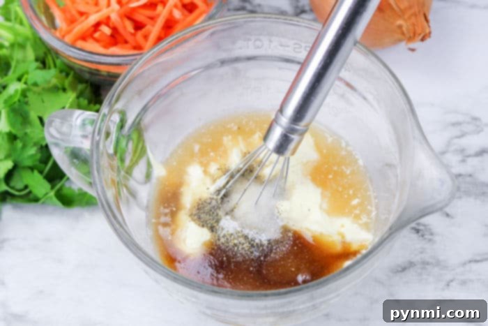 A bowl of creamy Hawaiian coleslaw dressing, showcasing its smooth texture and readiness to be mixed with vegetables.