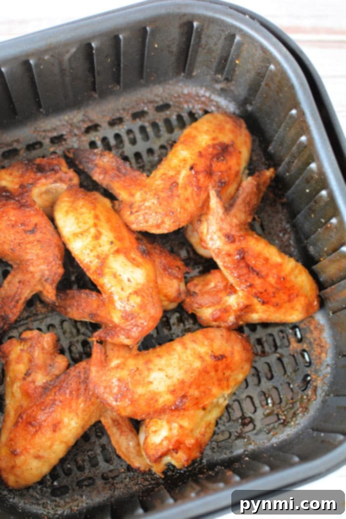 A close-up shot of crispy whole chicken wings, golden brown and glistening with seasoning.