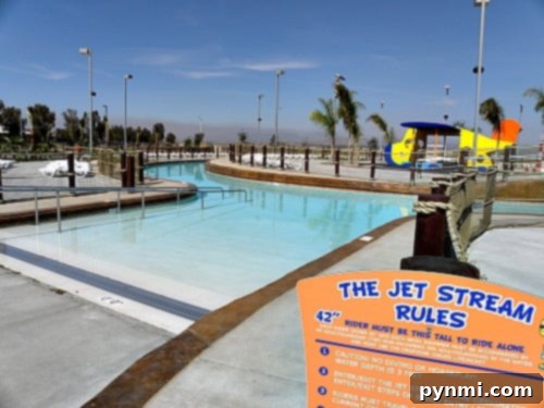 DropZone Perris Water Park: Is It Worth the Splash 4 A water park with a winding lazy river and a colorful play structure in the background. The foreground features a sign labeled "The Jet Stream Rules" with text about height and safety requirements, showcasing the fun and safety standards at Perris Water Park.