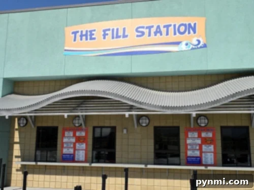 DropZone Perris Water Park: Is It Worth the Splash 9 The image shows an establishment called "The Fill Station" with a sign above and a wave-like awning, reminiscent of Perris Water Park. Below are three service windows with red menus posted on the wall. The building has a light green and yellow exterior.