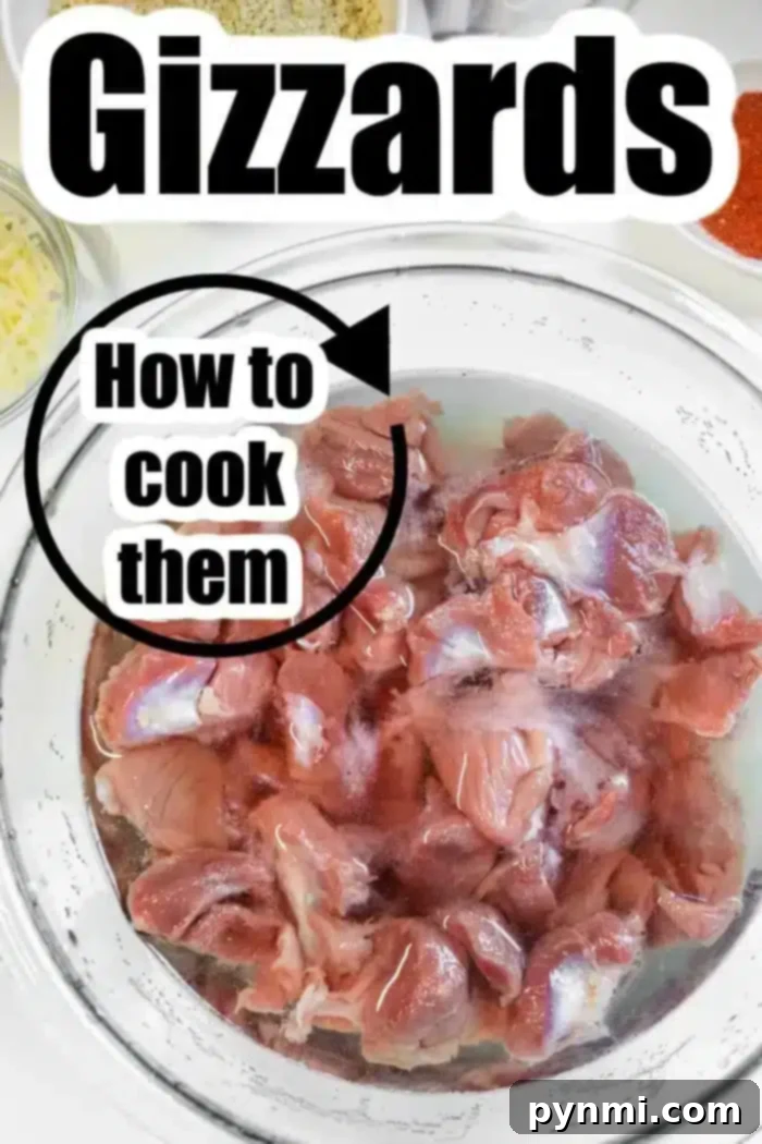 A glass bowl filled with raw chicken gizzards soaking in a salt water brine.