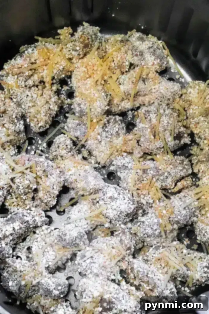 Close-up of uncooked, breaded chicken gizzards arranged neatly in a single layer within an air fryer basket, perfectly ready for cooking.