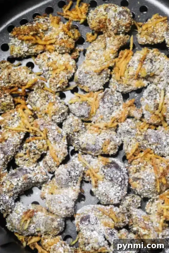 A perforated metal tray filled with a fresh batch of golden-brown, crispy breaded gizzards, just removed from the air fryer.