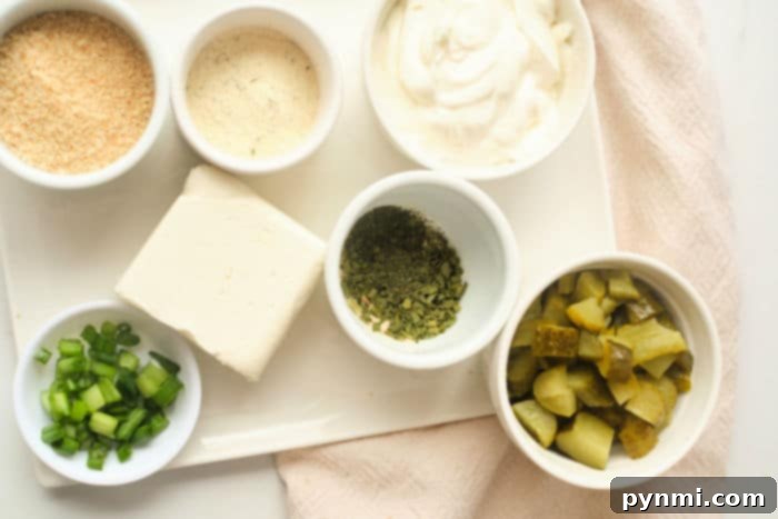A close-up of creamy Pickle and Ranch Dip in a white bowl, garnished with a few pickle slices and fresh dill sprigs.