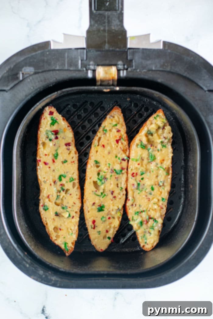 Crispy Golden Garlic Bread from Scratch 9 Three pieces of golden crispy garlic bread in an air fryer basket, garnished with fresh herbs and spices
