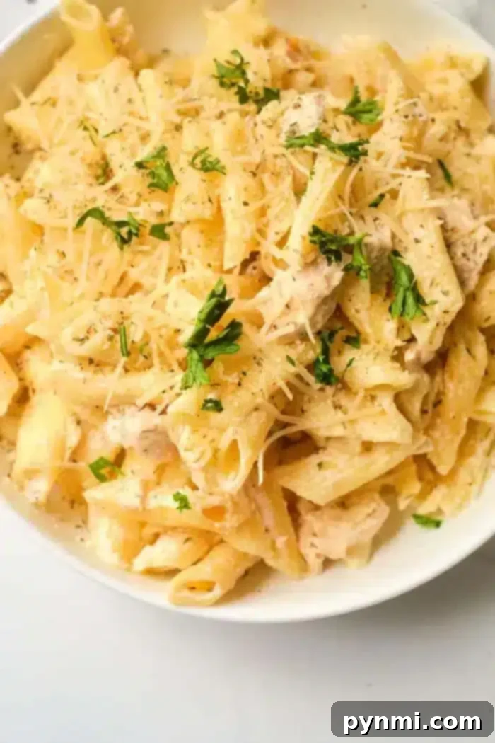 A bowl of creamy pasta topped with grated cheese and garnished with chopped herbs. The penne, mixed with a luxurious sauce, offers the comfort of homemade flavors, reminiscent of an Instant Pot creation.