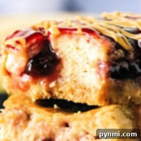 Close-up of a decadent Peanut Butter and Jelly Cheesecake Bar with a bite taken out, revealing its luscious layers of filling and topping.
